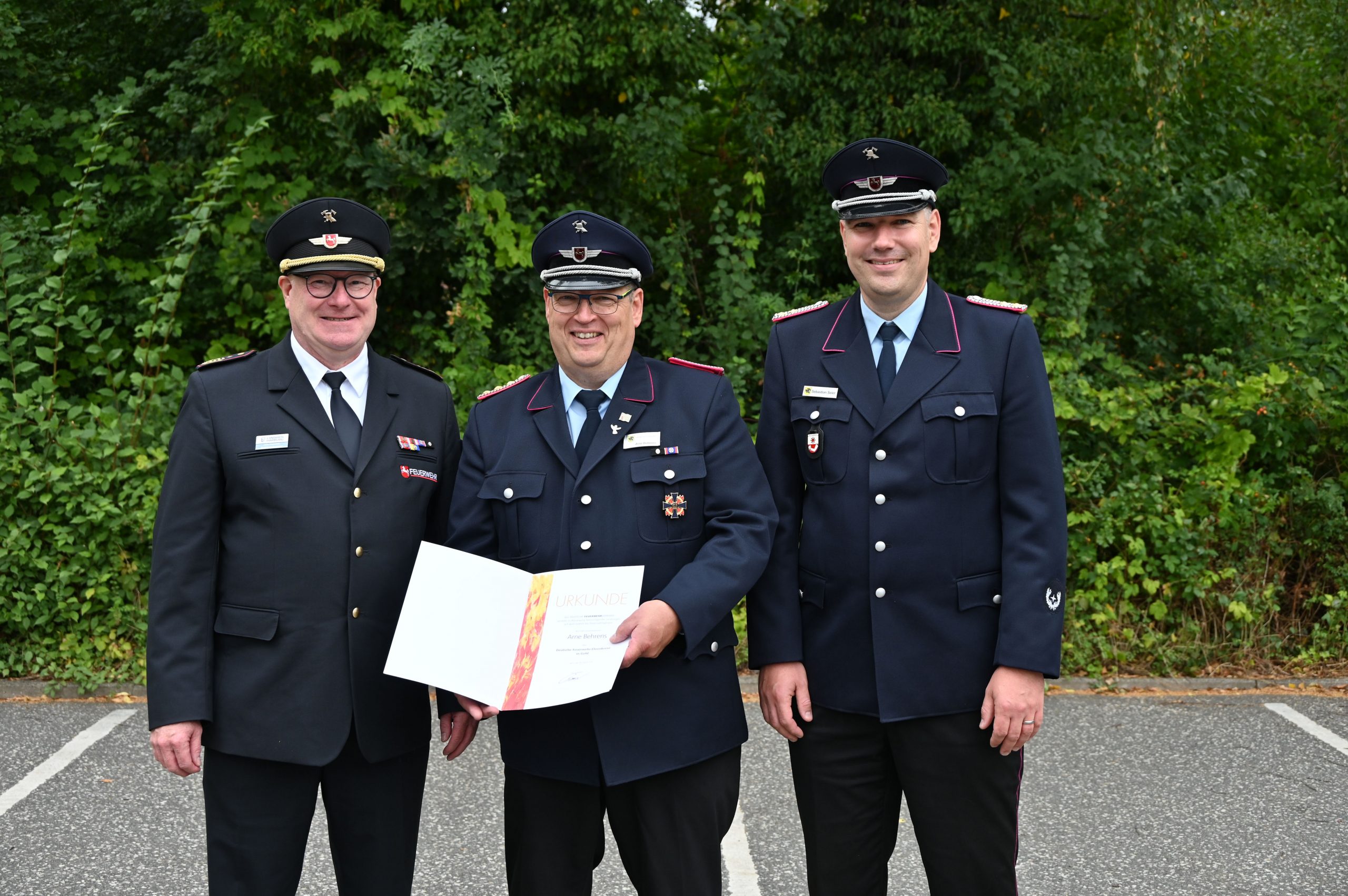 Der Geehrte Arne Behrens mit Kreisverbandsvorsitzendem Jörn Petersen und Gemeindebrandmeister Hanstedt Sebastian Seier